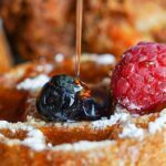 Waffles with powdered sugar, berries, and syrup