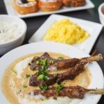 jamaican oxtails & grits with chicken & waffles in the background