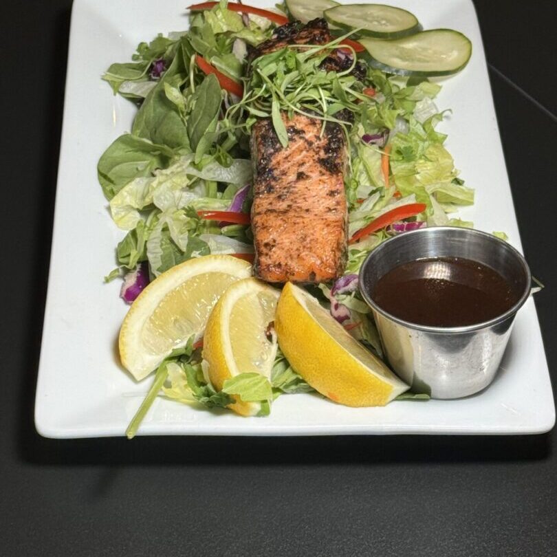 Grilled salmon salad with lemon wedges and dressing